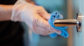 A cleaning person disinfecting a door handle